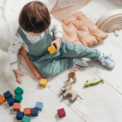 kind speelt op de grond met gekleurde blokken